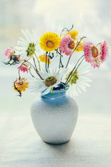 bouquet of flowers in vase on blue background