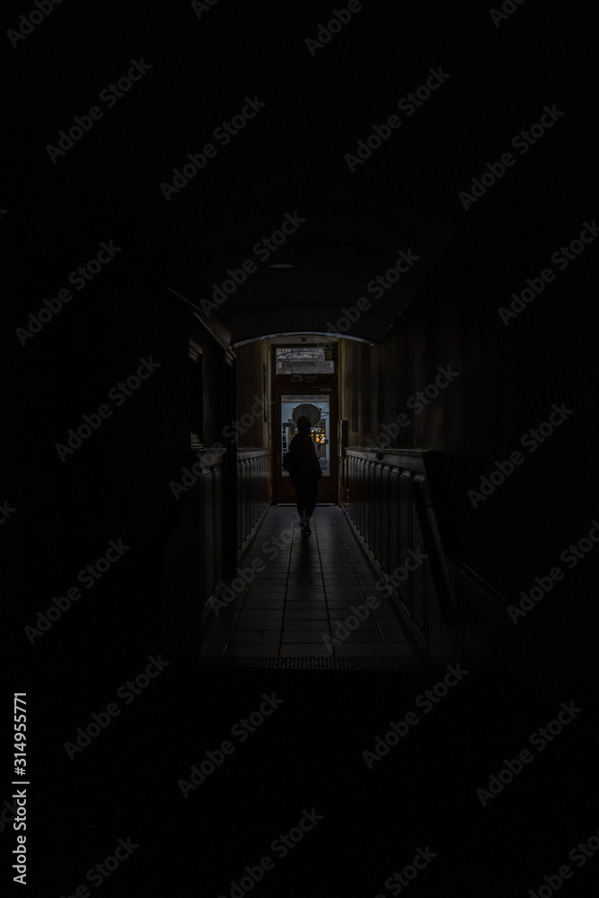 Wall mural silhouette of a person in the middle of a passageway inside a dimly lit building