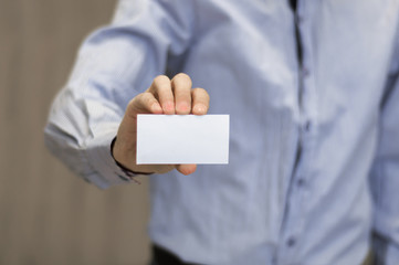 Young business man holding white business card on modern office blur background