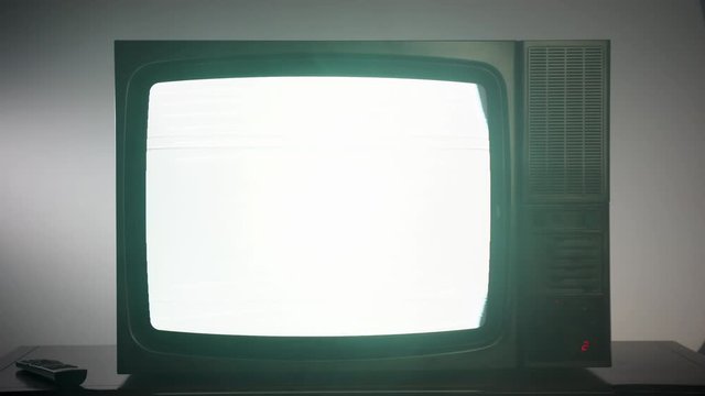 Old vintage television with blinking screen, old-fashioned black TV with static noise. Broken television and noise interference, old vintage TV and remote control