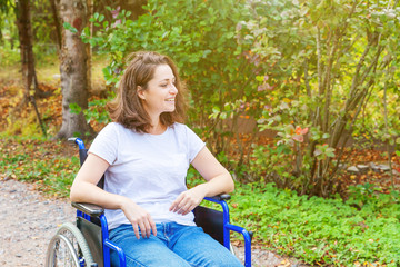 Young happy handicap woman in wheelchair on road in hospital park waiting for patient services....