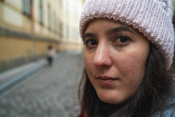 Detail of the face of a girl in a wool hat with a serious expression in the street