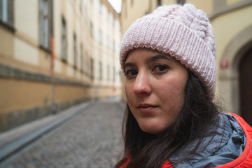 Girl in wool hat looking at camera with relaxed expression in the middle of the street