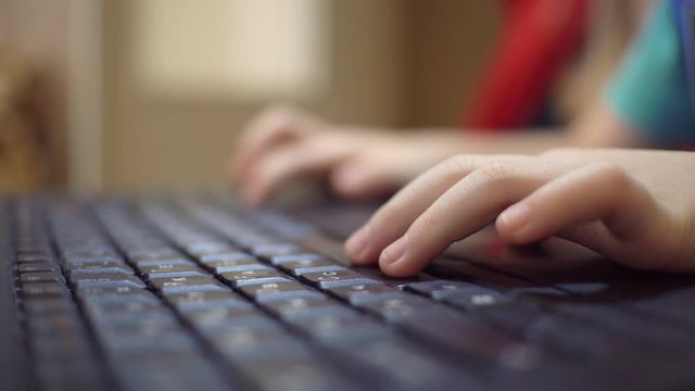A child plays a game on a laptop. hands on the keyboard close-up.