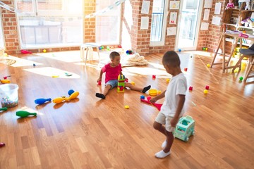 Adorable toddlers playing around lots of toys at kindergarten