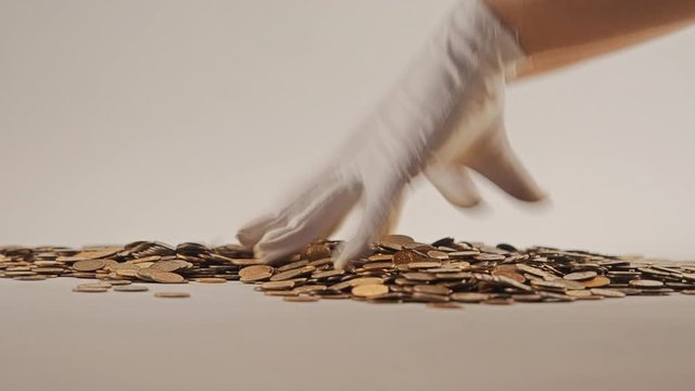 White-gloved hands scooping up a pile of gold coins. They sort out and scatter money.On white background. Garland. Money glitters.