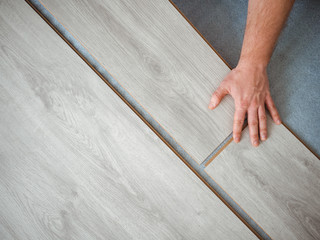 A man holds a laminate board in his hands. The repair process in the room