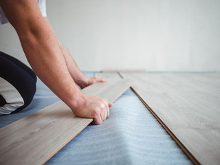 Fototapeta na wymiar The repair process in the apartment. Man laying laminate flooring