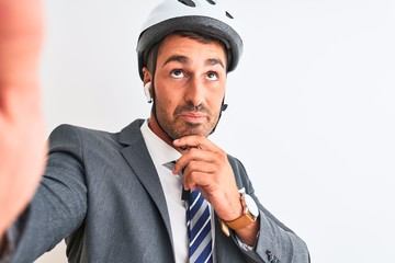 Young handsome business man wearing bike helmet taking a selfie over isolated background serious face thinking about question, very confused idea