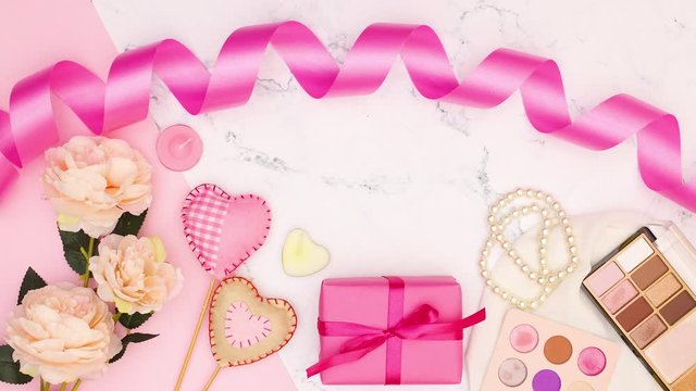 Pink ribbon, flowers, make up, gift and hearts appear on marble background - Stop motion 