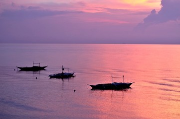 Traditional Filipino fishing boats offshore at sea at sunrise