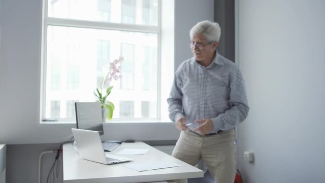 Tracking shot of calm elderly teacher in casual wear standing up explaining computer science and coding basics in school class