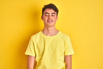 Teenager boy wearing yellow t-shirt over isolated background smiling looking to the side and staring away thinking.