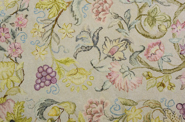 Detail of a vintage wool hooked rug with a botanical motiff with flowers, fruit and leafy vines