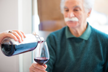 senior taking a glass of red wine