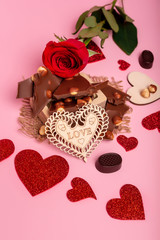Valentine's day background with red hearts, chocolate candies and red rose on a pink background. Romantic atmosphere. Love symbols.