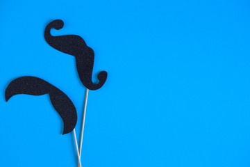 Obraz premium Paper mustache on a stick on a blue background. Holiday concept