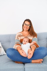 Fototapeta na wymiar Young beautiful woman and her baby on the sofa at home. Newborn and mother relaxing and resting comfortable
