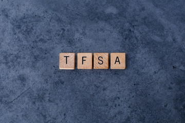 "TFSA" spelled out in wooden letter tiles on a dark rough background
