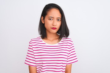 Fototapeta premium Young chinese woman wearing striped t-shirt standing over isolated white background skeptic and nervous, frowning upset because of problem. Negative person.