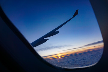 Naklejka na ściany i meble beautiful saturated sunset above the clouds on the porthole of the plane, the road to a new life, pacifying wallpaper, littered horizon 