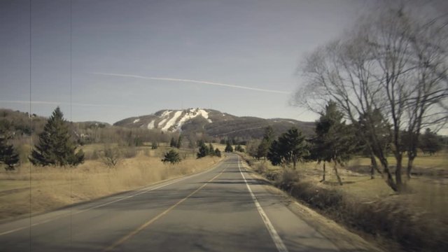 Moving on Country Road in Spring. Ski Mountain with Snow in Background. Vintage Effect, 8mm, 4K