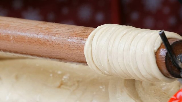 Female hands wrap the sticks of dough on a wooden stick. National Czech trdelnik sweet delicacy that is prepared on the street.Traditional Czech and Hungarian baking sweet bakery.