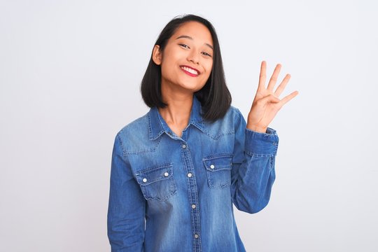 Young beautiful chinese woman wearing denim shirt standing over isolated white background showing and pointing up with fingers number four while smiling confident and happy.