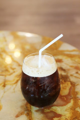 Black coffee with ice on table in cafe.