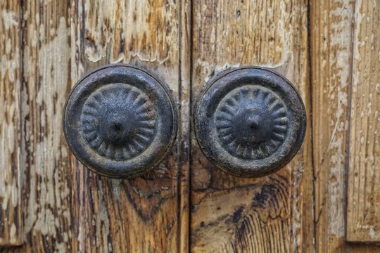 cast iron door knobs on old wooden door, in close up