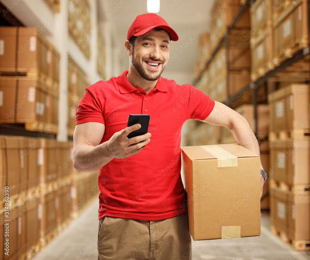 Canvas Prints Delivery guy holding a box and a mobile phone in a storage