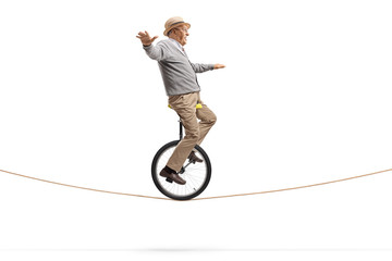 Elderly gentleman riding a unicycle on a rope © Ljupco Smokovski