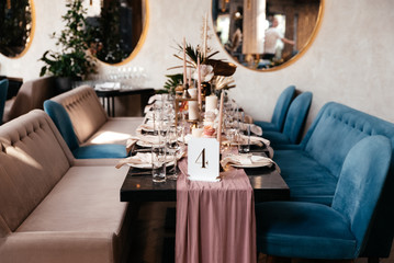 Wedding table decorated with various festive decorations such as flowers, candles, tablecloth and a nameplate with table number