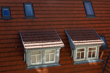 Roofs of European historic houses with skylights and orange tiles