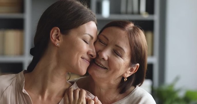 Tender loving old mum hugging kissing happy adult daughter, closeup
