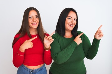 Young beautiful women wearing casual clothes standing over isolated white background smiling and looking at the camera pointing with two hands and fingers to the side.