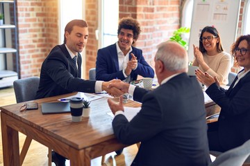Group of business workers smiling happy and confident in a meeting. Speaking with smile on face working together shaking hands for agreement at the office.