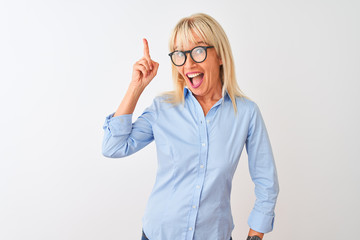 Middle age businesswoman wearing elegant shirt and glasses over isolated white background pointing finger up with successful idea. Exited and happy. Number one.