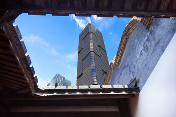 Upward view of the skyscrapers with blue sky background from a Chinese traditional courtyard