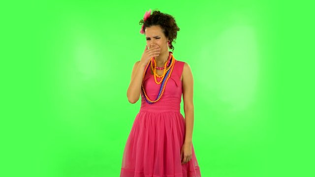 Woman showing disgust for bad smell on green background