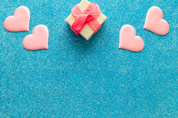 Valentines day pattern background flat lay  pink hearts and a gold gift box with rose ribbon on a glittering classic blue background with copy space. love wedding romantic concept, minimal top view