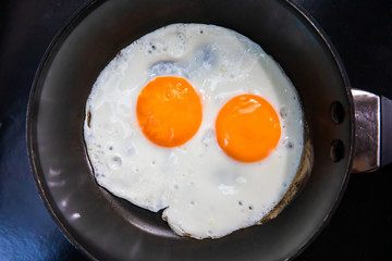 Two fried eggs in cast iron frying pan.