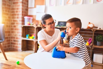 Beautiful teacher and toddler boy playing with vintage blue phone at kindergarten