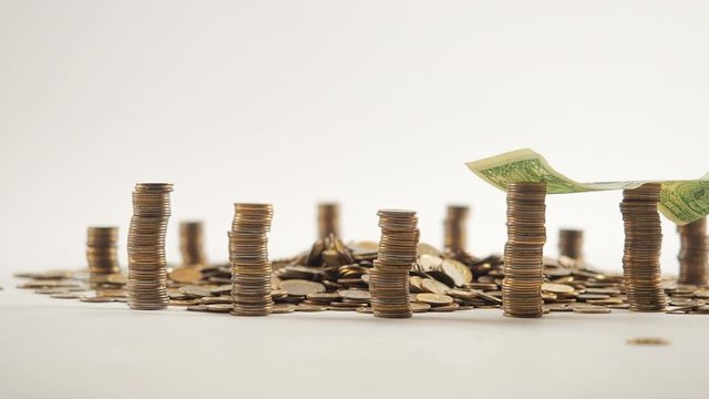The concept of money. Columns of gold coins in the form of skyscrapers or Stonehenge. Close-up hands make up stacks of coins. Smoke. Garland.