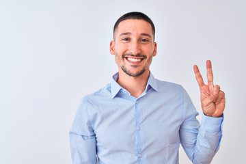 Young handsome business man standing over isolated background showing and pointing up with fingers number two while smiling confident and happy.