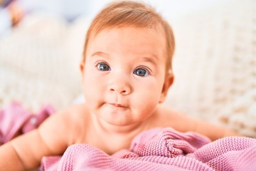 Adorable baby lying down over blanket on the sofa at home. Newborn relaxing and resting comfortable