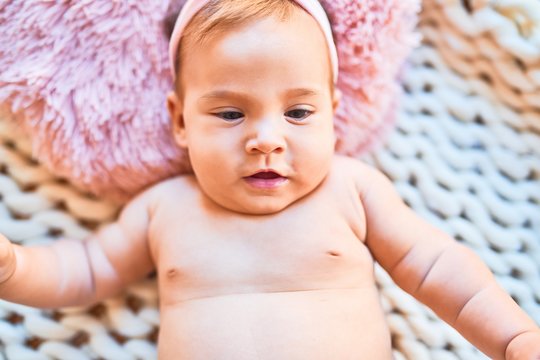Adorable baby lying down over blanket on the floor at home. Newborn relaxing and resting comfortable