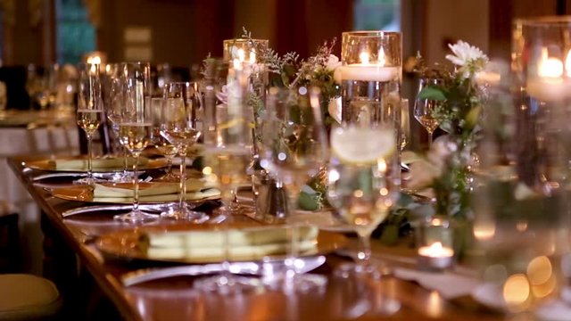 Wedding event banquet interior table setting details decorated with champagne flutes candles white roses flowers in glass vases filled with water