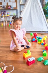 Young beautiful toddler sitting on the floor playing with building blocks at kindergaten