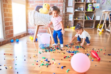 Adorable toddlers playing with building blocks toy at kindergarten